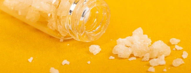 Cristaux de CBD purs renversés sur fond jaune & guide de consommation